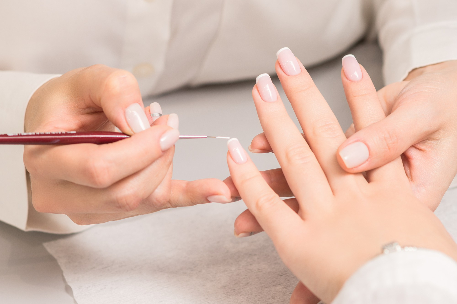 woman-receiving-french-manicure-by-beautician